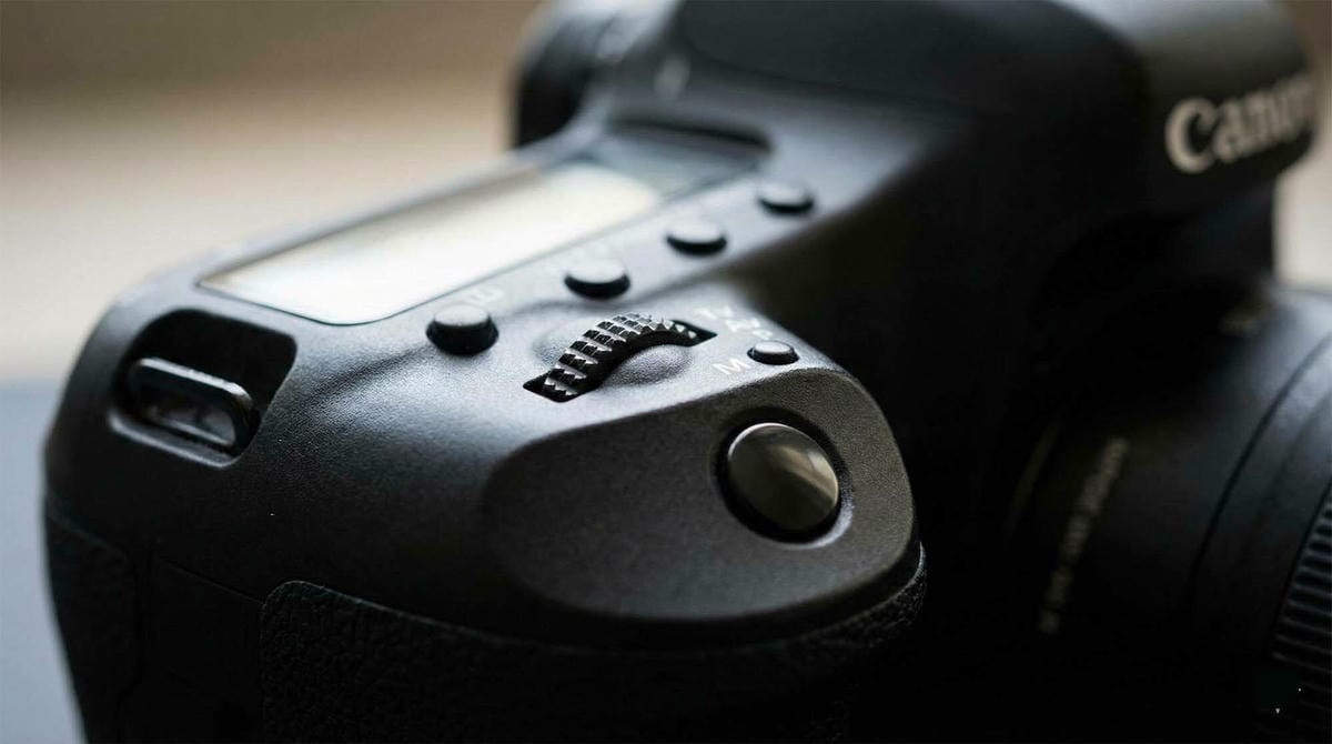 Canon DSLR 相機的快門與模式轉盤特寫，象徵經典單眼相機的質感與世代交替 / Close up of a Canon DSLR camera shutter button and mode dial, highlighting the transition from classic DSLR to mirrorless.